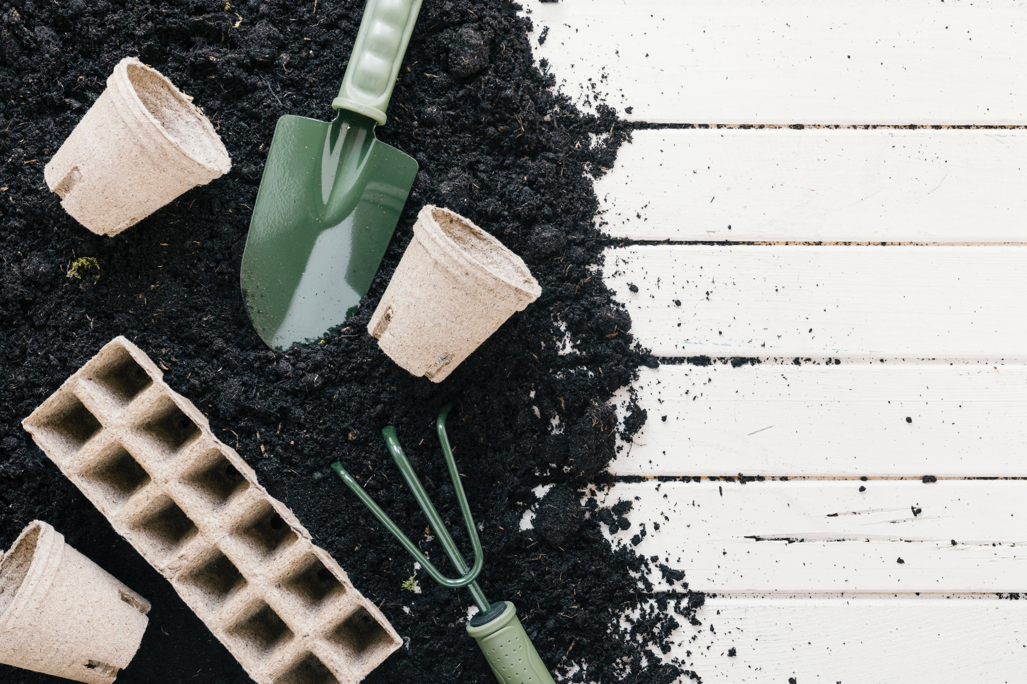peat-pot-and-peat-tray-black-soil-with-gardening-shovel-gardening-rake-over-wooden-desk.jpg